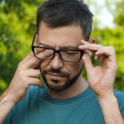 Man suffering from dry eyes outdoors on a sunny day
