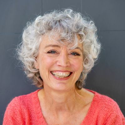 close up portrait of a happy older woman smiling against a gray wall