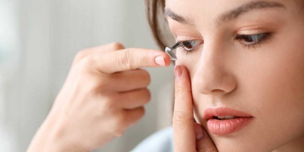 young woman putting in a contact lens.
