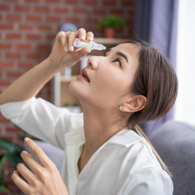 Young woman using eye drops suffering from dry eyes