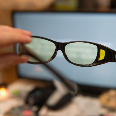 POV of a person holding computer glasses in front of a computer screen