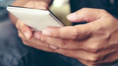 Close-up of a man's hands using a smartphone.