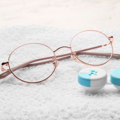 glasses and a contacts lens case laying on a cloth