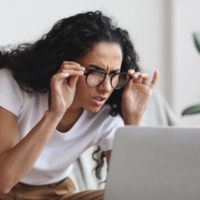 woman squinting through her glasses trying to read her laptop screen