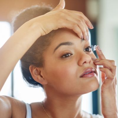 young woman putting in her contact lenses at home