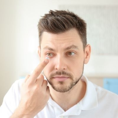 man putting in a daily contact lens