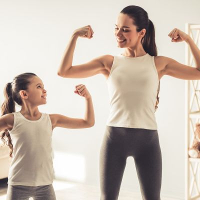 Woman flexing her arms with her young daughter.