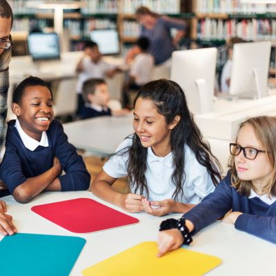 students sitting at a table working with construction paper.