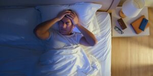 Man laying in bed at sunrise frustrated because he can't sleep