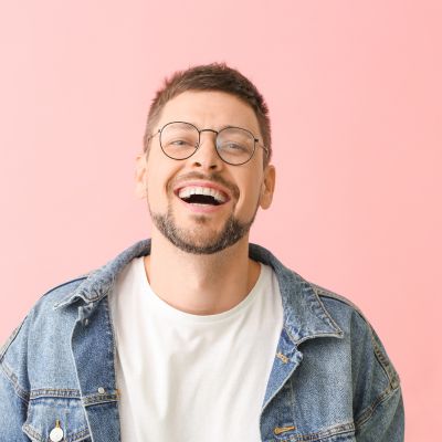 Smiling man wearing glasses against a colored background