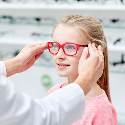 optician putting glasses on a little girl's face