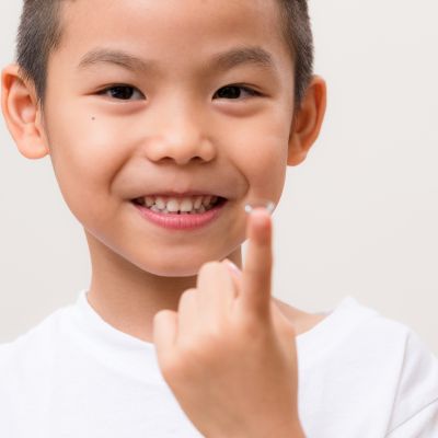 little kid holding a contact lens on the tip of his finger