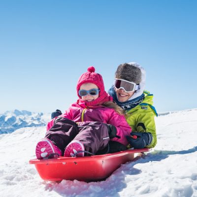 smiling brother and sister riding a sled