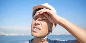 man wearing a helmet outdoors holding up his eyes to shield